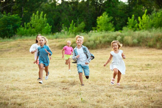 Niños, niños corriendo en la pradera a la luz del sol de verano.