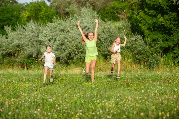 Niños, niños corriendo en la pradera a la luz del sol de verano.