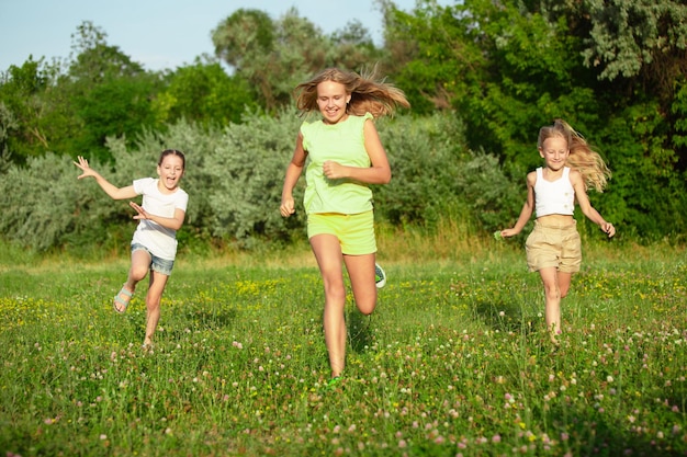 Niños, niños corriendo en la pradera en la luz del sol del verano