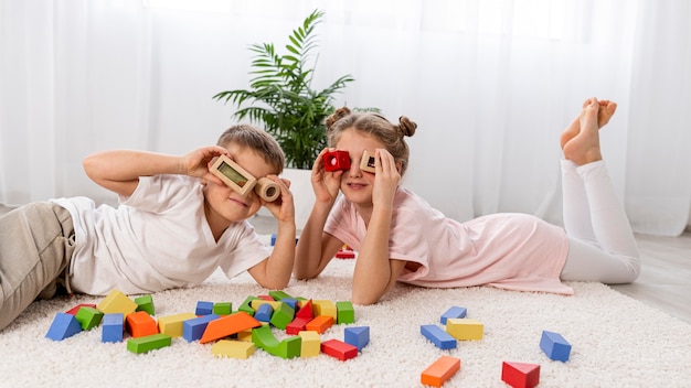 Foto gratuita niños no binarios jugando con un juego colorido en casa.