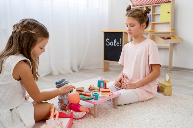 Foto gratuita niños no binarios jugando un juego de cumpleaños con una muñeca.