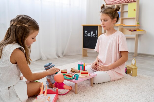 Niños no binarios jugando un juego de cumpleaños con una muñeca.