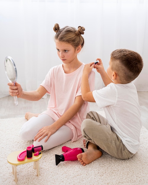 Foto gratuita niños no binarios jugando un juego de salón de belleza.