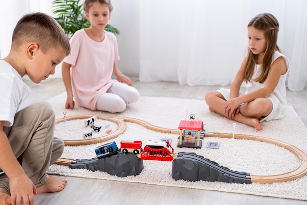 Niños no binarios jugando con juegos de autos en interiores.