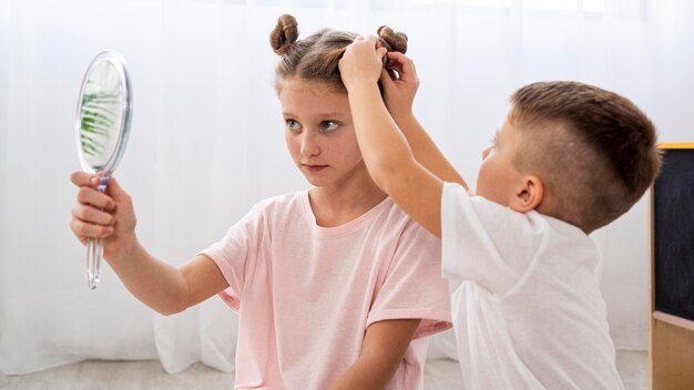 Niños no binarios jugando juntos a un juego de salón de belleza