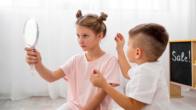 Niños no binarios jugando juntos a un juego de salón de belleza