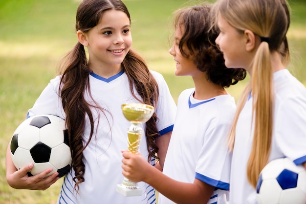 Niños obteniendo un trofeo después de ganar un partido de fútbol.