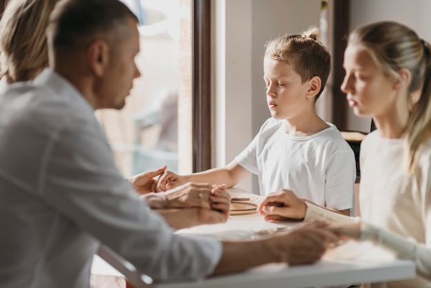 Niños y padres rezando antes de comer.