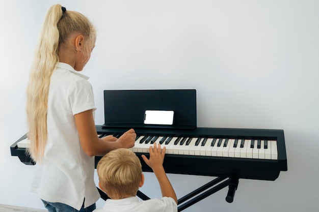 Niños pequeños aprendiendo a tocar el piano