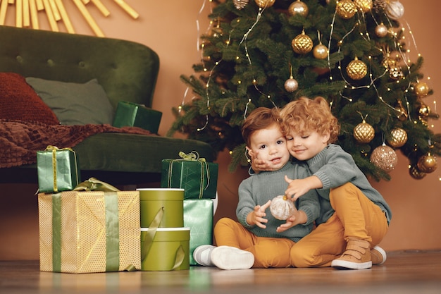 Niños pequeños cerca del árbol de navidad en un suéter gris