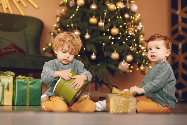 Niños pequeños cerca del árbol de navidad en un suéter gris