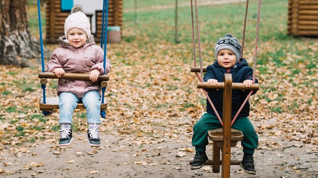 Niños pequeños columpiándose en balancín de madera