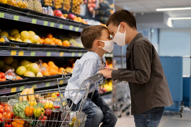 Niños pequeños de compras con máscaras