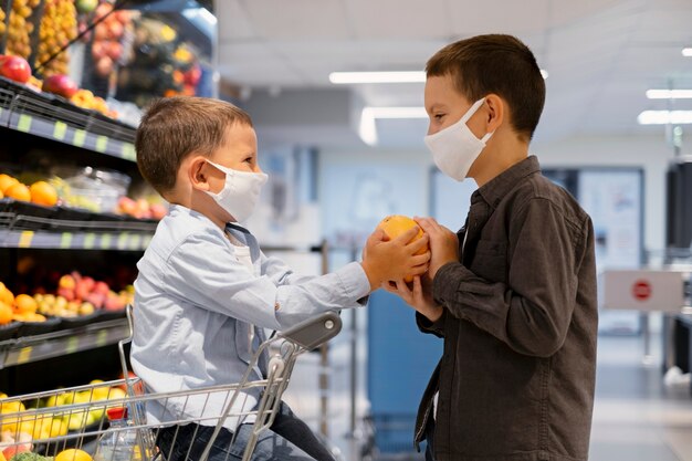 Niños pequeños de compras con máscaras