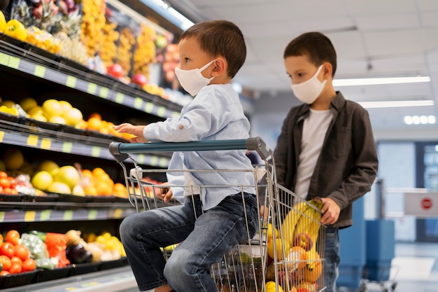 Niños pequeños de compras con máscaras