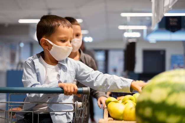 Niños pequeños de compras con máscaras