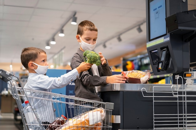 Niños pequeños de compras con máscaras