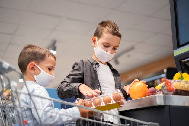 Niños pequeños de compras con máscaras