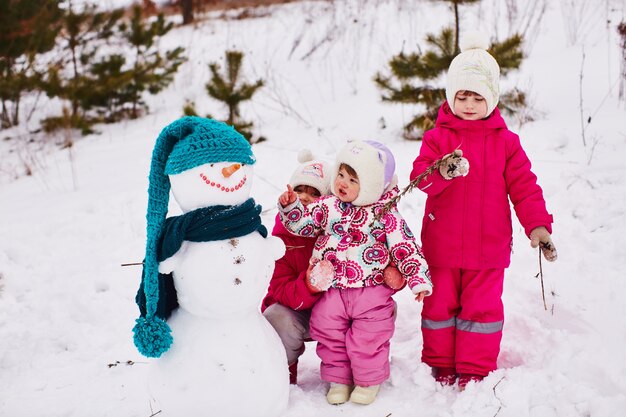 Los niños pequeños están mirando a un hermoso muñeco de nieve