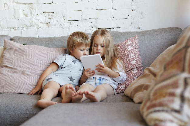 Los niños pequeños felices están sentados en la sala de estar