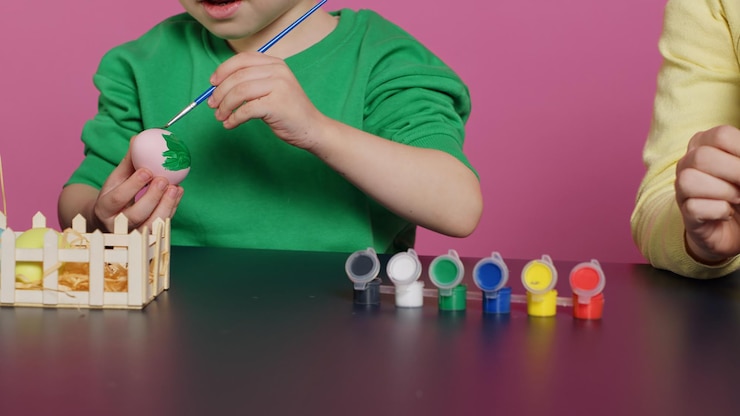 Foto gratuito niños pequeños felices pintando huevos con acuarela y sellos