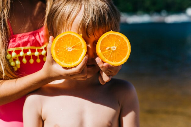 Foto gratuita niños pequeños jugando con naranja en la playa