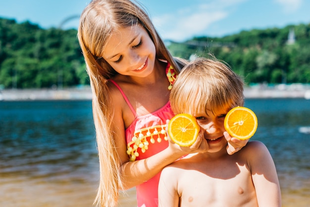 Niños pequeños jugando con rodajas de naranja en la playa