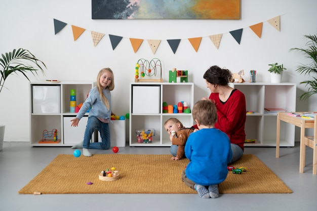 Foto gratuita niños pequeños y maestros de tiro completo en el interior