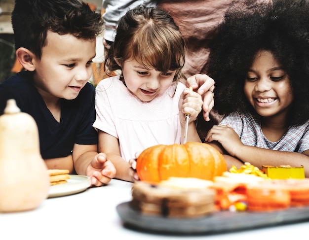 Niños pequeños tallando Halloween jack-o-lanterns