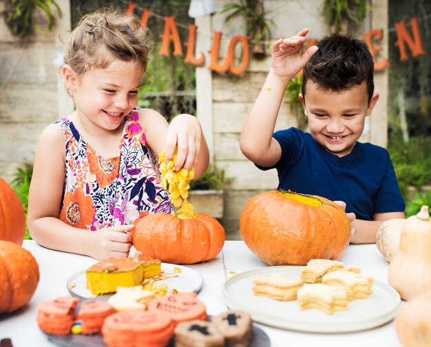 Niños pequeños tallando Halloween jack-o-lanterns