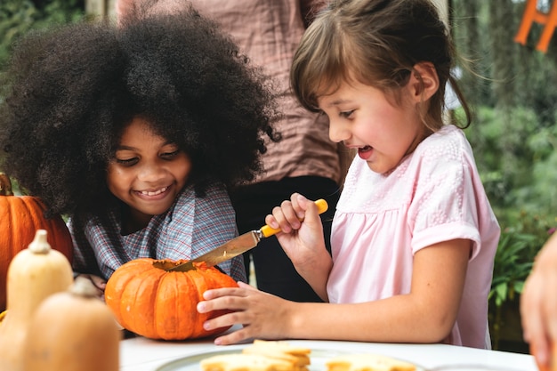 Niños pequeños tallando Halloween jack-o-lanterns