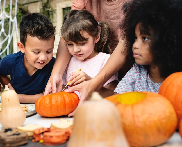 Niños pequeños tallando Halloween jack-o-lanterns