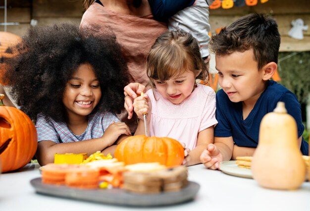 Niños pequeños tallando Halloween jack-o-lanterns