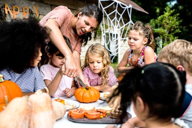 Niños pequeños tallando Halloween jack-o-lanterns