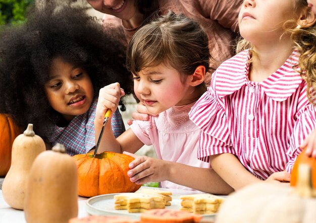 Niños pequeños tallando Halloween jack-o-lanterns