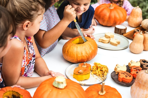 Niños pequeños tallando Halloween jack-o-lanterns