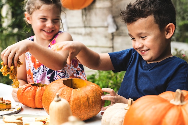 Niños pequeños tallando Halloween jack-o-lanterns