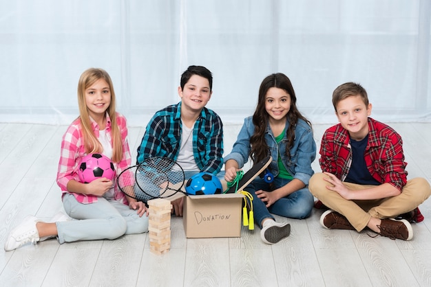 Foto gratuita niños en el piso con caja de donación