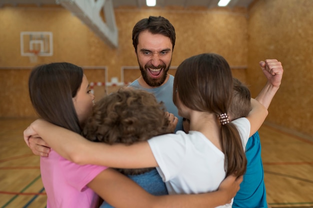 Niños y profesor de educación física sonriente.