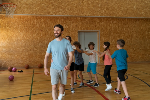 Foto gratuita niños y profesor de tiro completo en el gimnasio