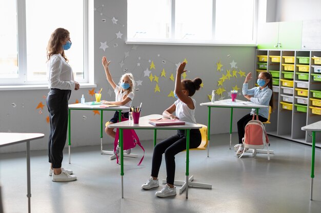 Niños que quieren responder una pregunta en clase.