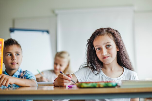 Niños que se sientan en el escritorio de la escuela