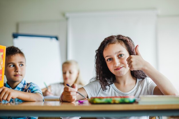 Niños que se sientan en el escritorio de la escuela