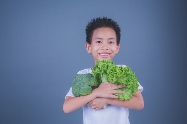 Niños que sostienen verduras en un fondo gris.