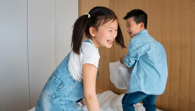 Niños que tienen tiro medio de pelea de almohadas