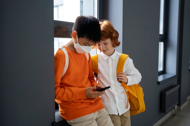 Foto gratuita niños que usan teléfonos inteligentes en la escuela