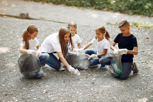 Los niños recogen basura en bolsas de basura en el parque