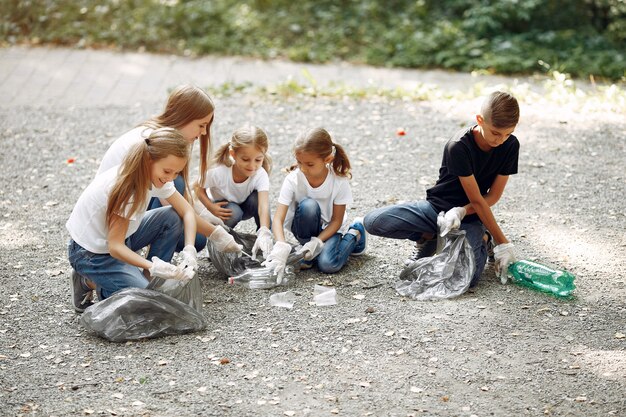 Los niños recogen basura en bolsas de basura en el parque