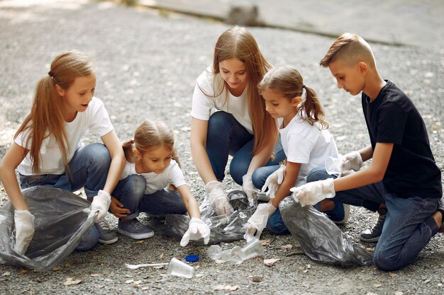 Los niños recogen basura en bolsas de basura en el parque