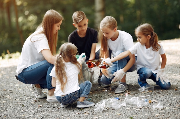 Los niños recogen basura en bolsas de basura en el parque